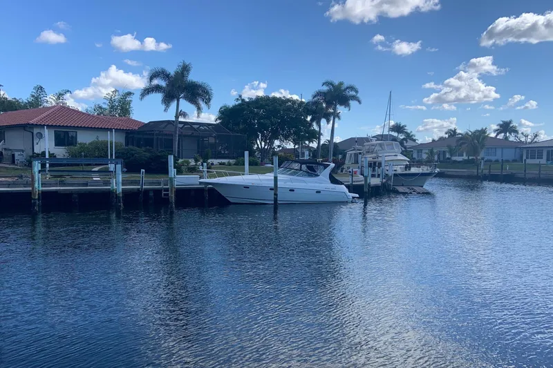 Slide: The Image of 1998 Cruisers 3375 Esprit docked by waterfront homes under a clear blue sky. - 4