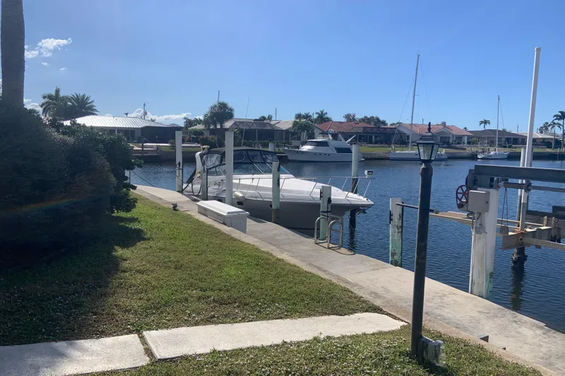 Slide: The Image of 1998 Cruisers 3375 Esprit docked at a sunny marina with waterfront homes. - 5