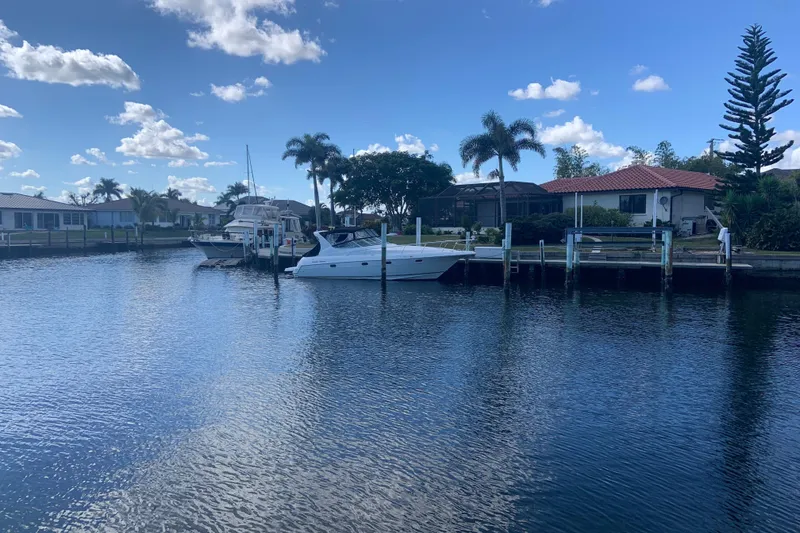 Slide: The Image of 1998 Cruisers 3375 Esprit docked by waterfront homes under a clear blue sky. - 7