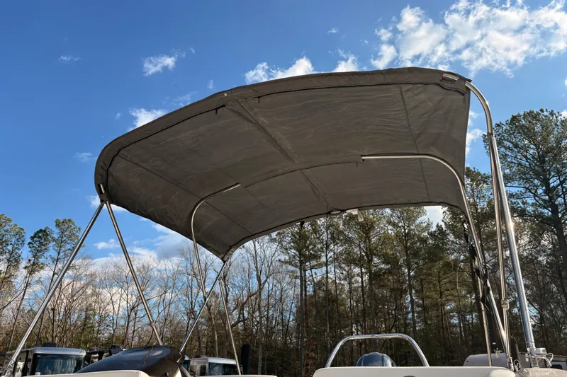 Slide: The Image of 2022 Hurricane SunDeck Sport 185 OB boat with canopy against blue sky and trees. - 12