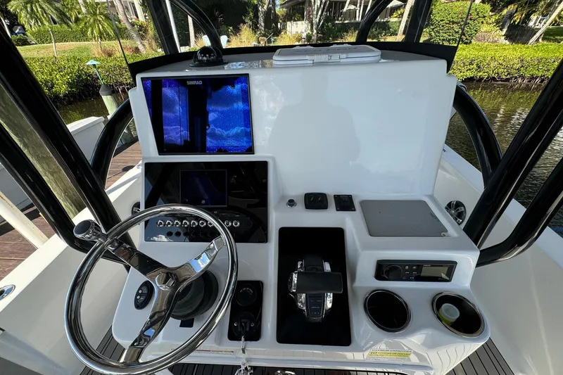 Slide: The Image of 2019 Sea Pro 248 Bay boat console with steering wheel, controls, and navigation screens. - 2
