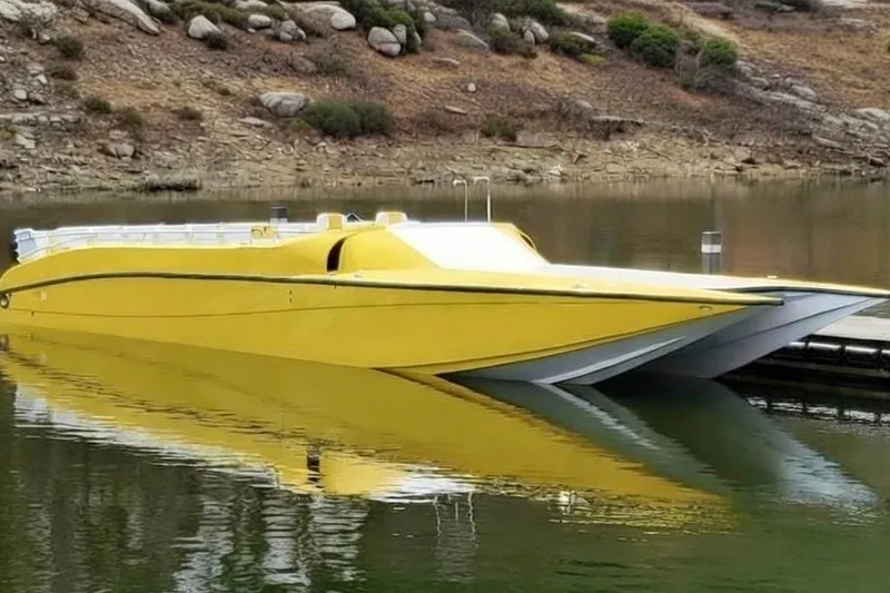 The Image of Yellow 2005 Thriller Powerboats Super Cat 55 moored on calm water near rocky shoreline. - 1
