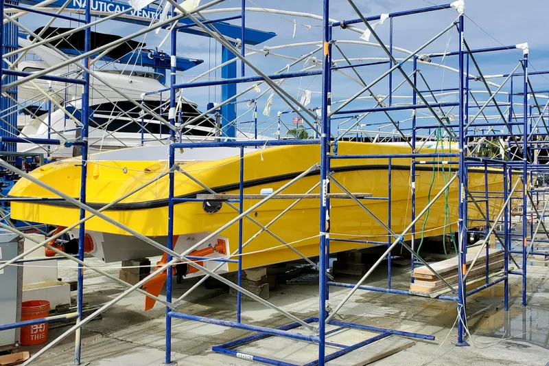 Slide: The Image of Yellow 2005 Thriller Powerboats Super Cat 55 under scaffolding at a marina. - 14