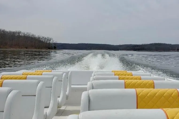 Slide: The Image of 2005 Thriller Powerboats Super Cat 55 cruising on a serene lake with white and yellow seating. - 6