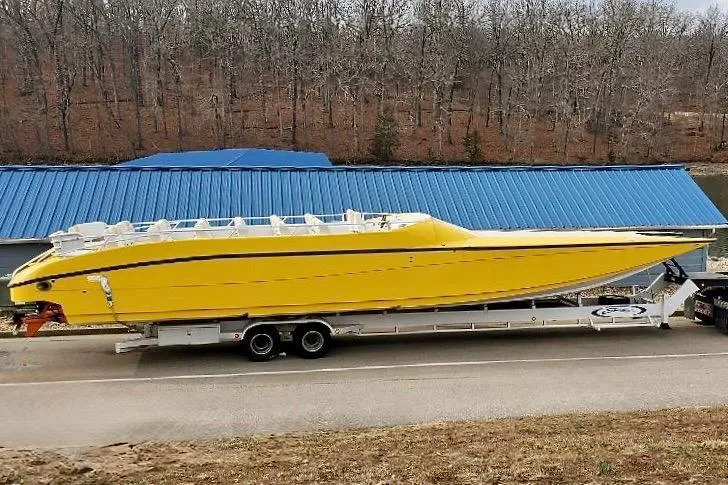Slide: The Image of Yellow 2005 Thriller Powerboats Super Cat 55 on trailer, parked near blue-roofed building. - 9