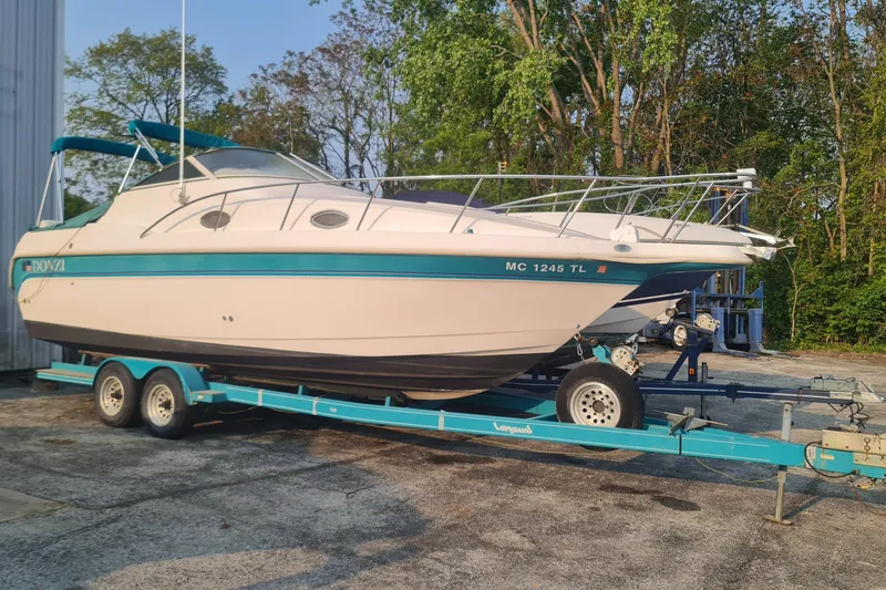 The Image of 1996 Donzi 275 LXC boat on trailer, parked outdoors near trees. - 1