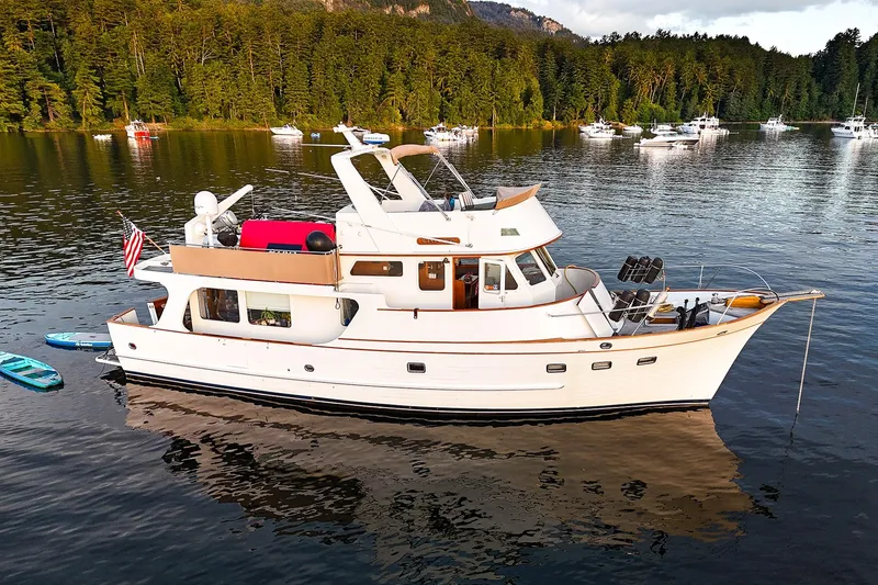 The Image of Classic 1973 American Marine Alaskan 53 yacht on serene lake with forest backdrop. - 0