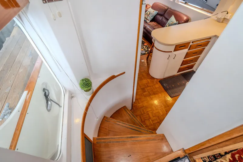 Slide: The Image of Interior view of 1973 American Marine Alaskan 53 yacht, featuring curved staircase and cozy living area. - 16