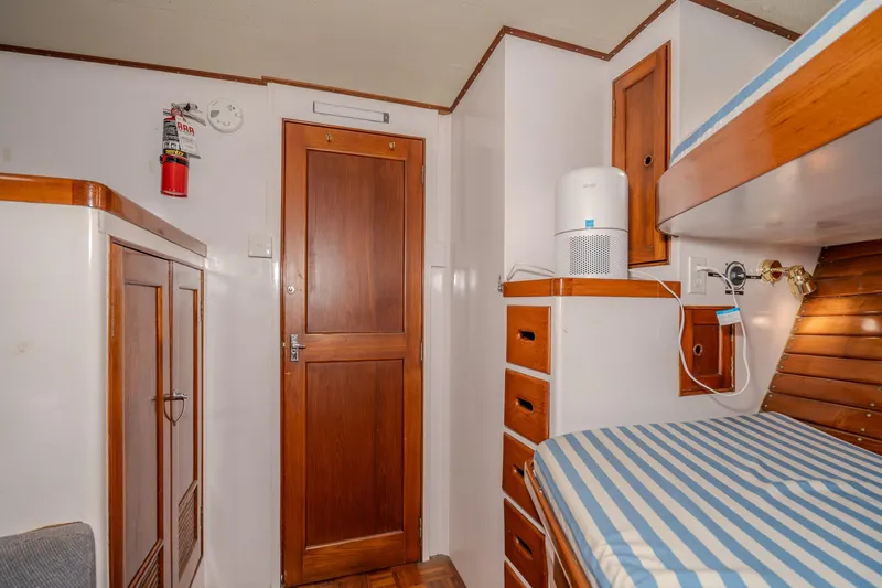 Slide: The Image of Interior of 1973 American Marine Alaskan 53 yacht with wooden cabinetry and striped bedding. - 29