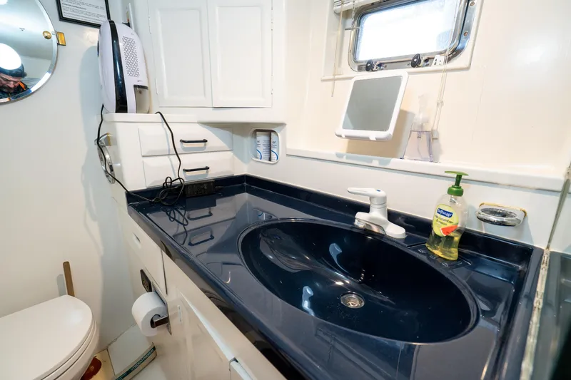 Slide: The Image of Bathroom interior of 1973 American Marine Alaskan 53 yacht with dark countertop and white cabinets. - 37