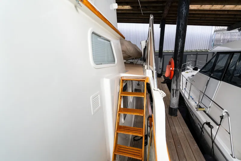 Slide: The Image of 1973 American Marine Alaskan 53 yacht with wooden ladder and docked alongside another boat. - 54