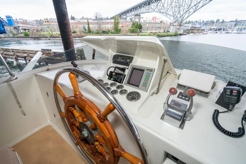 Slide: The Image of 1973 American Marine Alaskan 53 yacht helm with wooden wheel and control panel, under a bridge. - 68