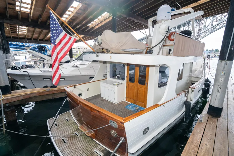 Slide: The Image of 1973 American Marine Alaskan 53 yacht docked, featuring wooden accents and an American flag. - 83