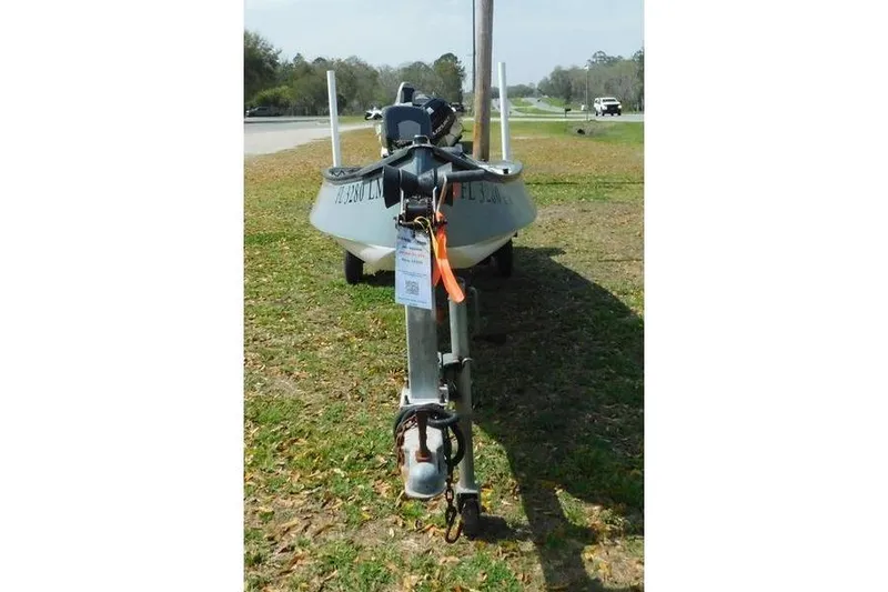 Slide: The Image of 2001 Gheenoe 13 boat on trailer, parked on grassy area near road. - 2