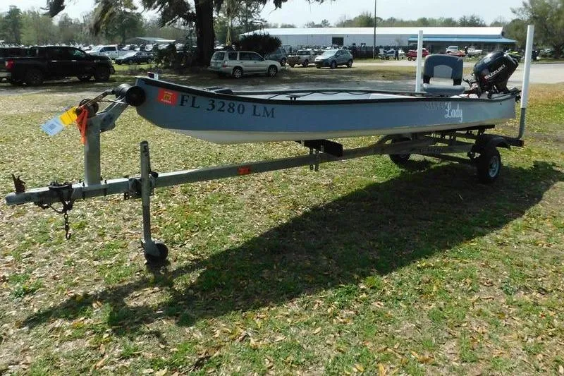 Slide: The Image of 2001 Gheenoe 13 boat on trailer, parked on grass with trees and cars in background. - 3