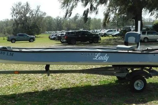 Slide: The Image of 2001 Gheenoe 13 boat on trailer, parked outdoors with trees and cars in the background. - 4
