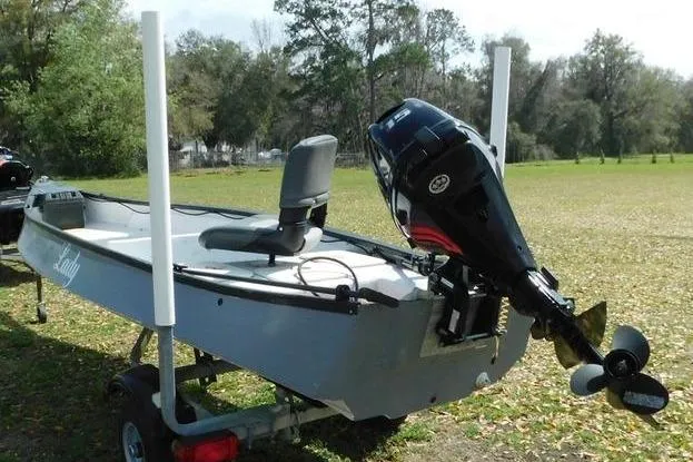Slide: The Image of 2001 Gheenoe 13 boat with motor on trailer, parked on grassy area. - 5