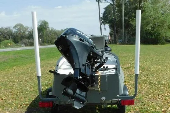 Slide: The Image of 2001 Gheenoe 13 boat with outboard motor on trailer, parked on grassy area. - 6