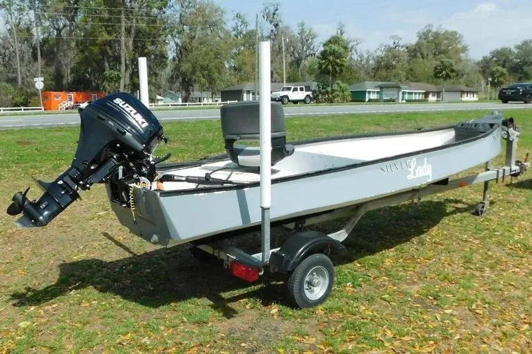 Slide: The Image of 2001 Gheenoe 13 boat with Suzuki motor on trailer, parked on grassy area. - 8