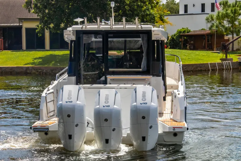 Slide: The Image of 2025 Wellcraft 38 Explorer boat with triple outboard engines on a calm waterway. - 10