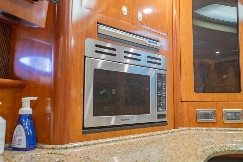 Slide: The Image of 2005 Sea Ray 420 Sundancer kitchen with microwave and wooden cabinetry. - 21