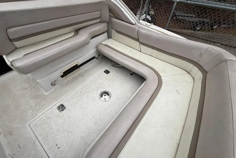 Slide: The Image of 1997 Four Winns 238 Vista boat interior with beige seating and storage compartments. - 16