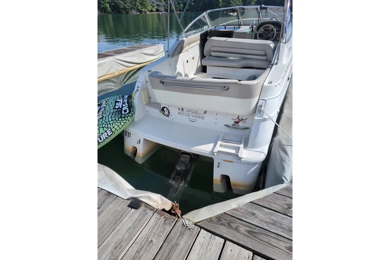 Slide: The Image of 1997 Four Winns 238 Vista boat docked, rear view with seating and steering wheel visible. - 2