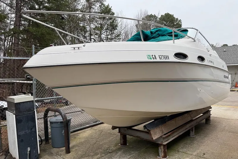 Slide: The Image of 1997 Four Winns 238 Vista boat on a stand, surrounded by trees and fencing. - 4