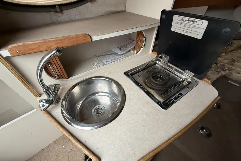 Slide: The Image of Compact kitchenette in a 1997 Four Winns 238 Vista boat with sink and stove. - 9