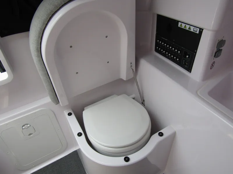 Slide: The Image of 2024 Axopar 25 Cross Top boat interior with compact marine toilet. - 23
