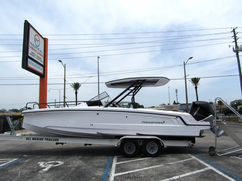 Slide: The Image of 2024 Axopar 25 Cross Top boat on a trailer in a parking lot. - 1