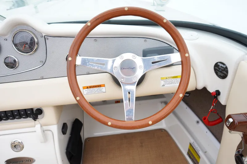Slide: The Image of 2015 Chris-Craft Lancer 20 dashboard with wooden steering wheel and gauges. - 13