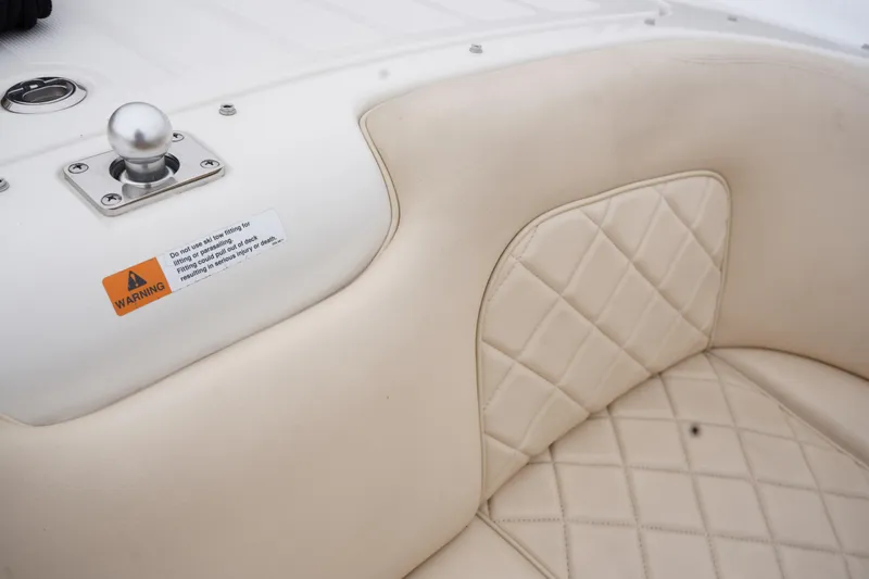 Slide: The Image of 2015 Chris-Craft Lancer 20 interior with quilted beige seating and warning label. - 24
