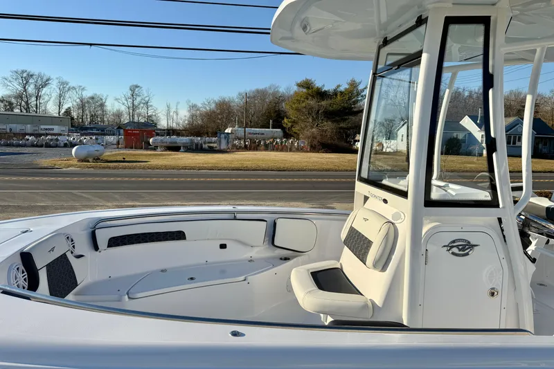 Slide: The Image of 2026 Tidewater 220 LXF boat interior with seating and console, parked outdoors. - 10