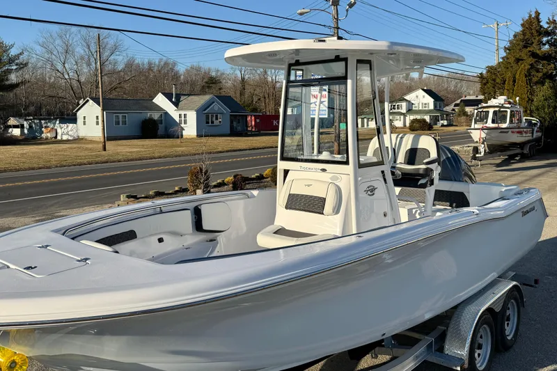 Slide: The Image of 2026 Tidewater 220 LXF boat on trailer, parked near road with houses in background. - 9