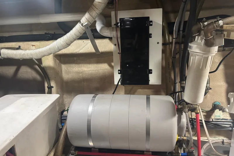 Slide: The Image of Engine room of a 1989 Grand Banks 46 Classic yacht, featuring mechanical components and piping. - 141