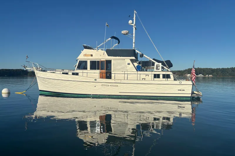Slide: The Image of 1989 Grand Banks 46 Classic yacht on calm water, clear sky reflection. - 17