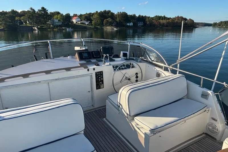 Slide: The Image of 1989 Grand Banks 46 Classic yacht helm with seating, overlooking serene water and shoreline. - 47