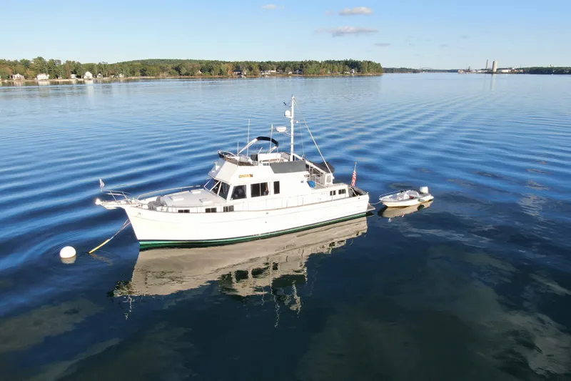 Slide: The Image of 1989 Grand Banks 46 Classic yacht anchored on calm water with a small boat nearby. - 5