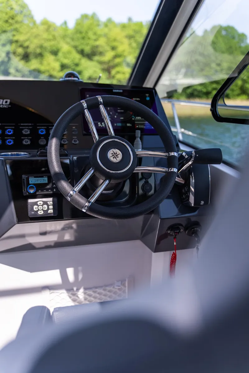 Slide: The Image of Interior view of Nautic 880 boat, 2025 model, with scenic lake and sky through windows. - 12