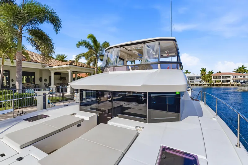 Slide: The Image of 2023 Leopard 46 Powercat yacht docked by waterfront homes and palm trees. - 1