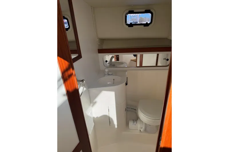 Slide: The Image of 2024 NorthCoast 285 HT boat bathroom with compact design, featuring a toilet and sink. - 14