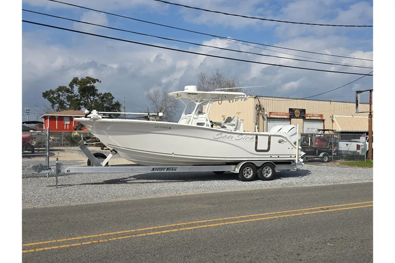 Slide: The Image of 2023 Sea Fox 288 Commander boat on trailer, parked near industrial buildings. - 2