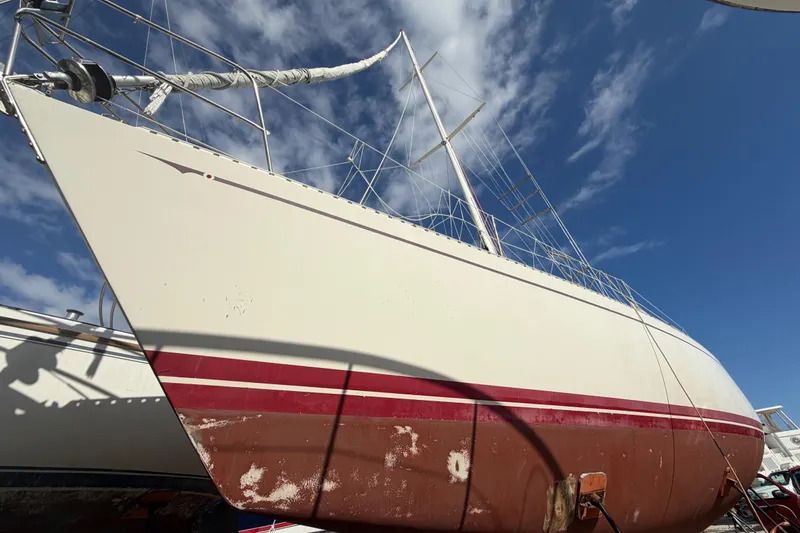 The Image of 1983 Morgan Catilina sailboat with red stripe, docked under a clear blue sky. - 0