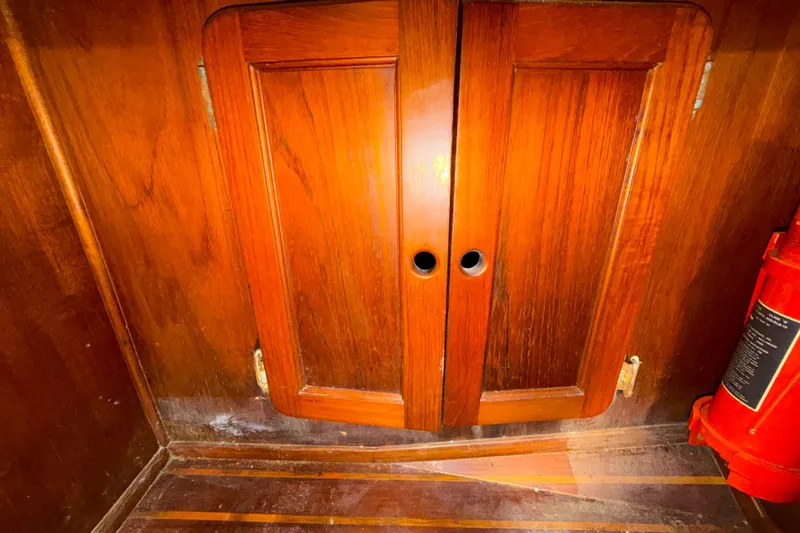Slide: The Image of Wooden cabinet doors inside a 1983 Morgan Catilina boat, with a fire extinguisher nearby. - 127