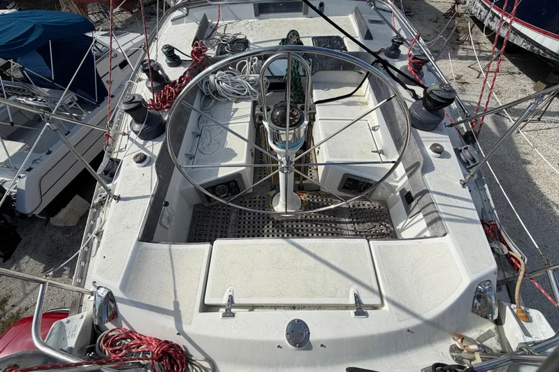 Slide: The Image of 1983 Morgan Catilina sailboat cockpit with steering wheel and ropes, docked in a marina. - 15