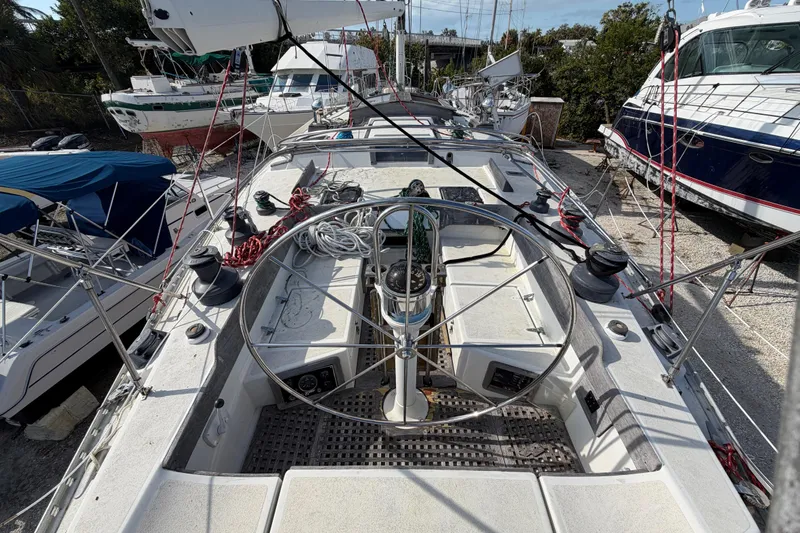 Slide: The Image of 1983 Morgan Catilina sailboat deck with steering wheel and rigging, docked among other boats. - 16