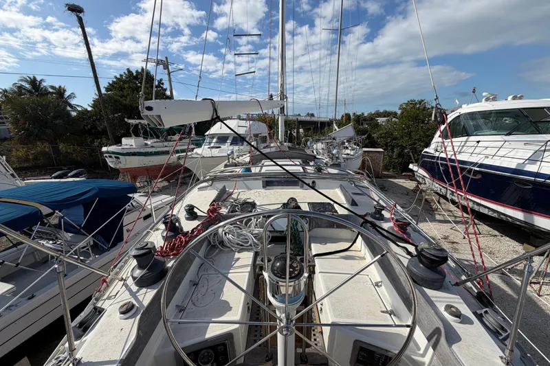 Slide: The Image of 1983 Morgan Catilina sailboat deck with steering wheel, docked among other boats under a blue sky. - 17