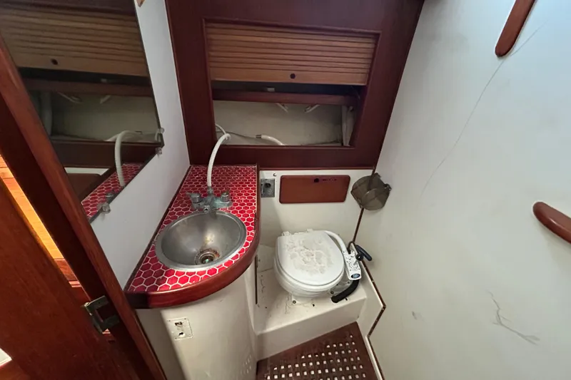 Slide: The Image of 1983 Morgan 45 Catalina yacht bathroom with sink, toilet, and red-tiled countertop. - 202