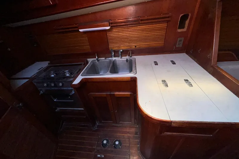 Slide: The Image of 1983 Morgan 45 Catalina yacht kitchen with dual sinks, stove, and wooden cabinetry. - 211